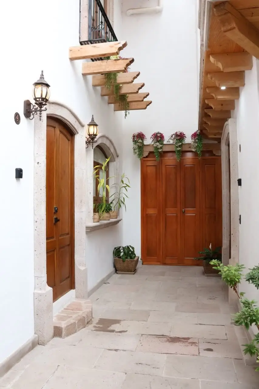 Pasillo interior con puertas de madera y buganvilias colgantes