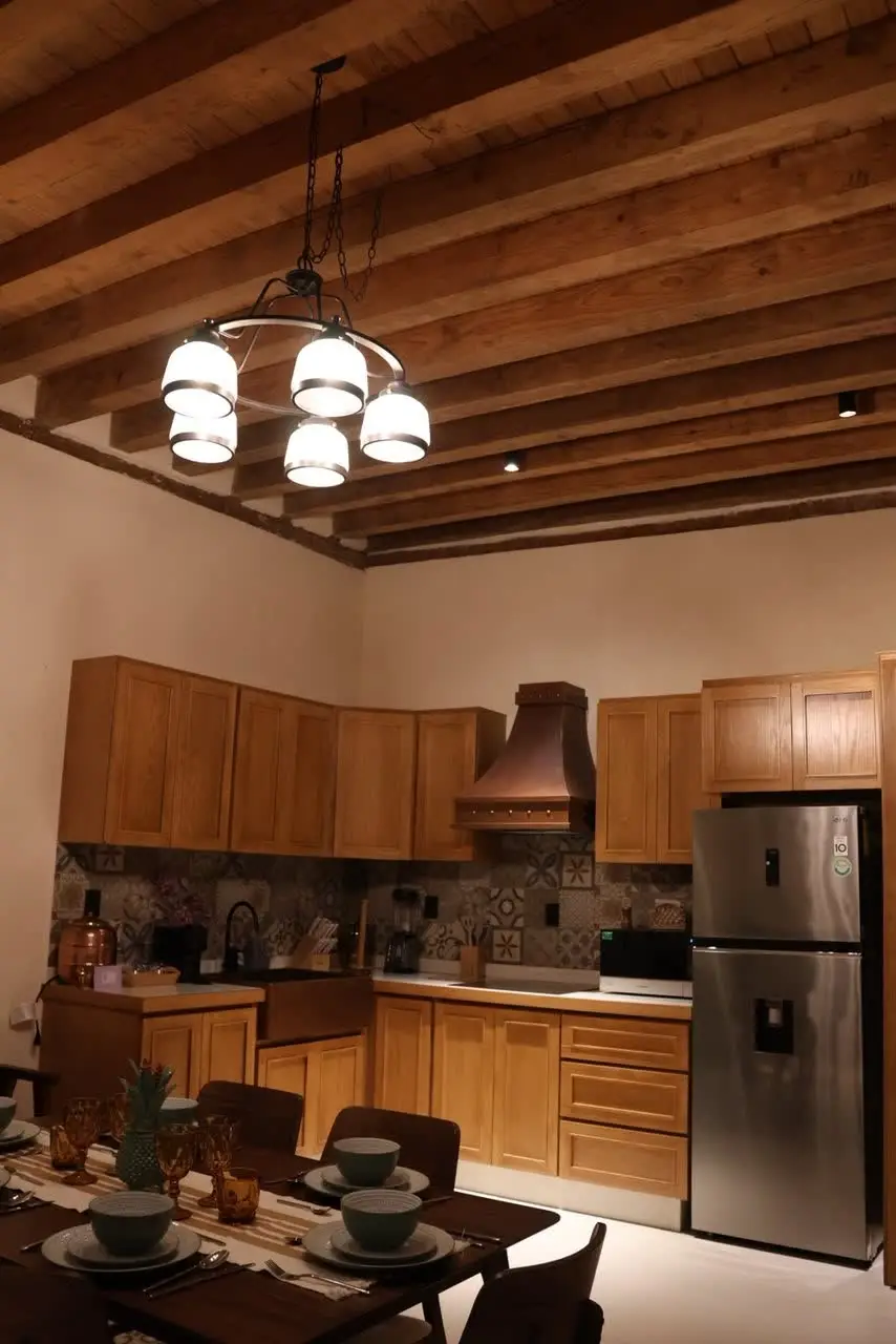 Cocina con lámpara colgante, campana de cobre y refrigerador