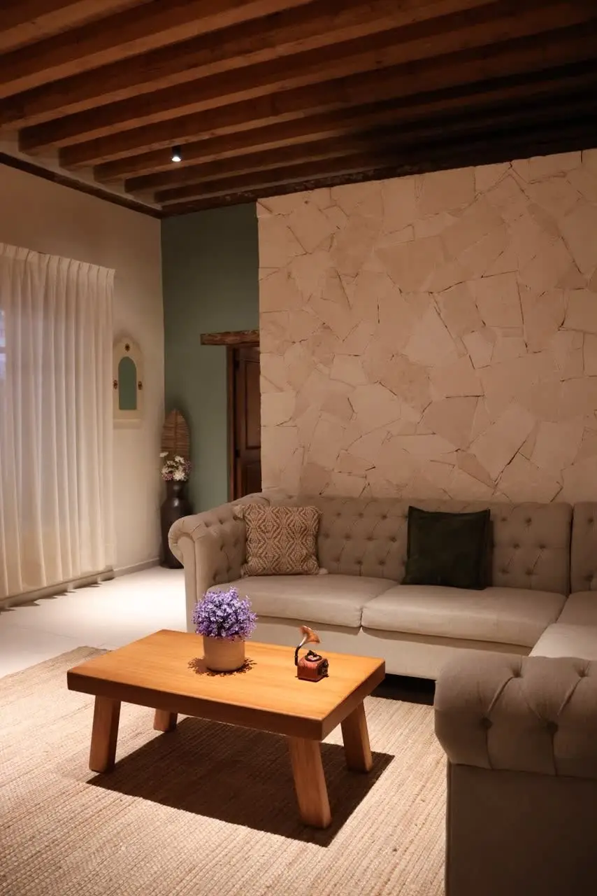 Sala con muro de piedra y sofá chesterfield