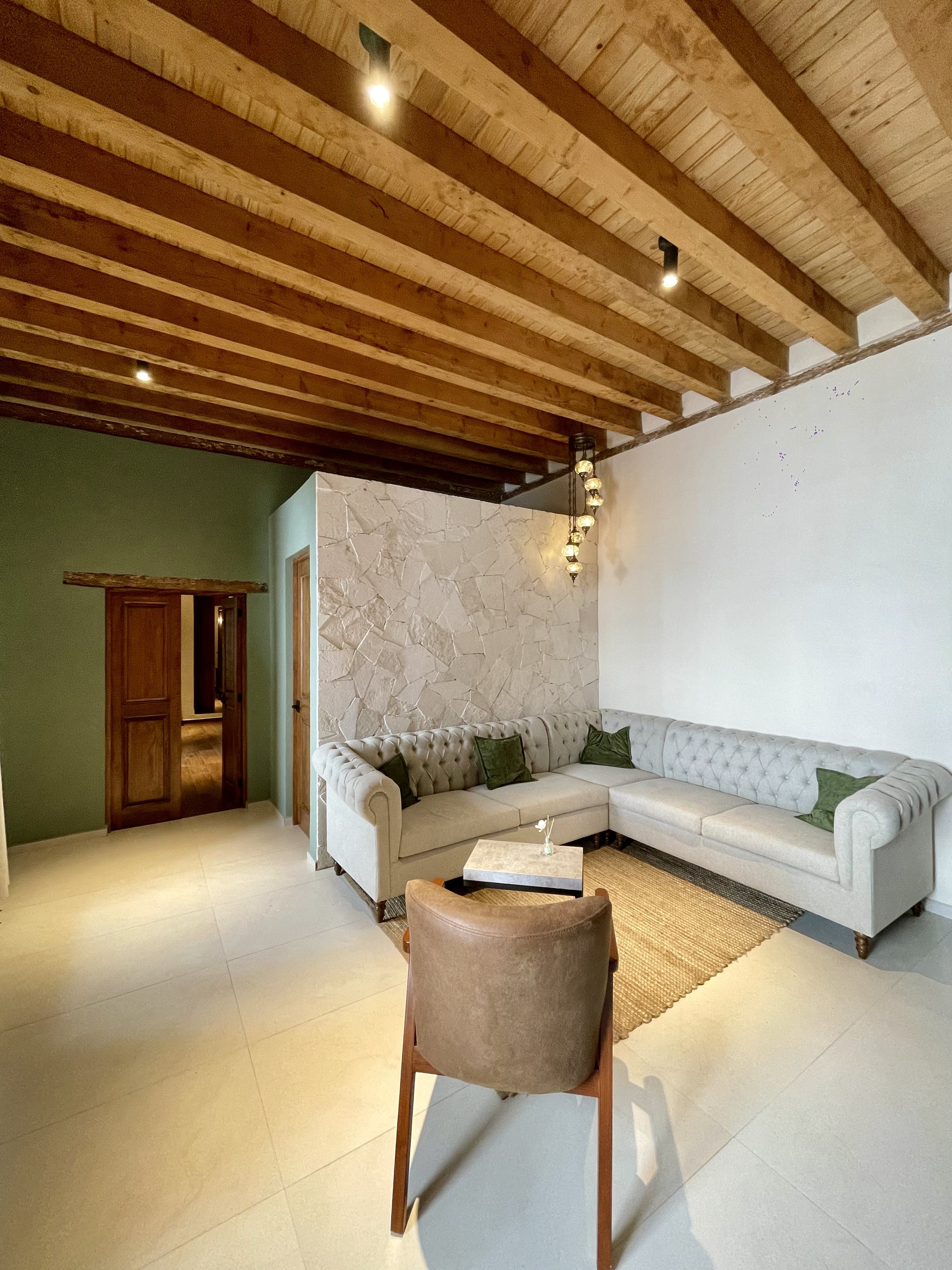 Sala del Departamento 1, con muro de piedra y vigas de madera