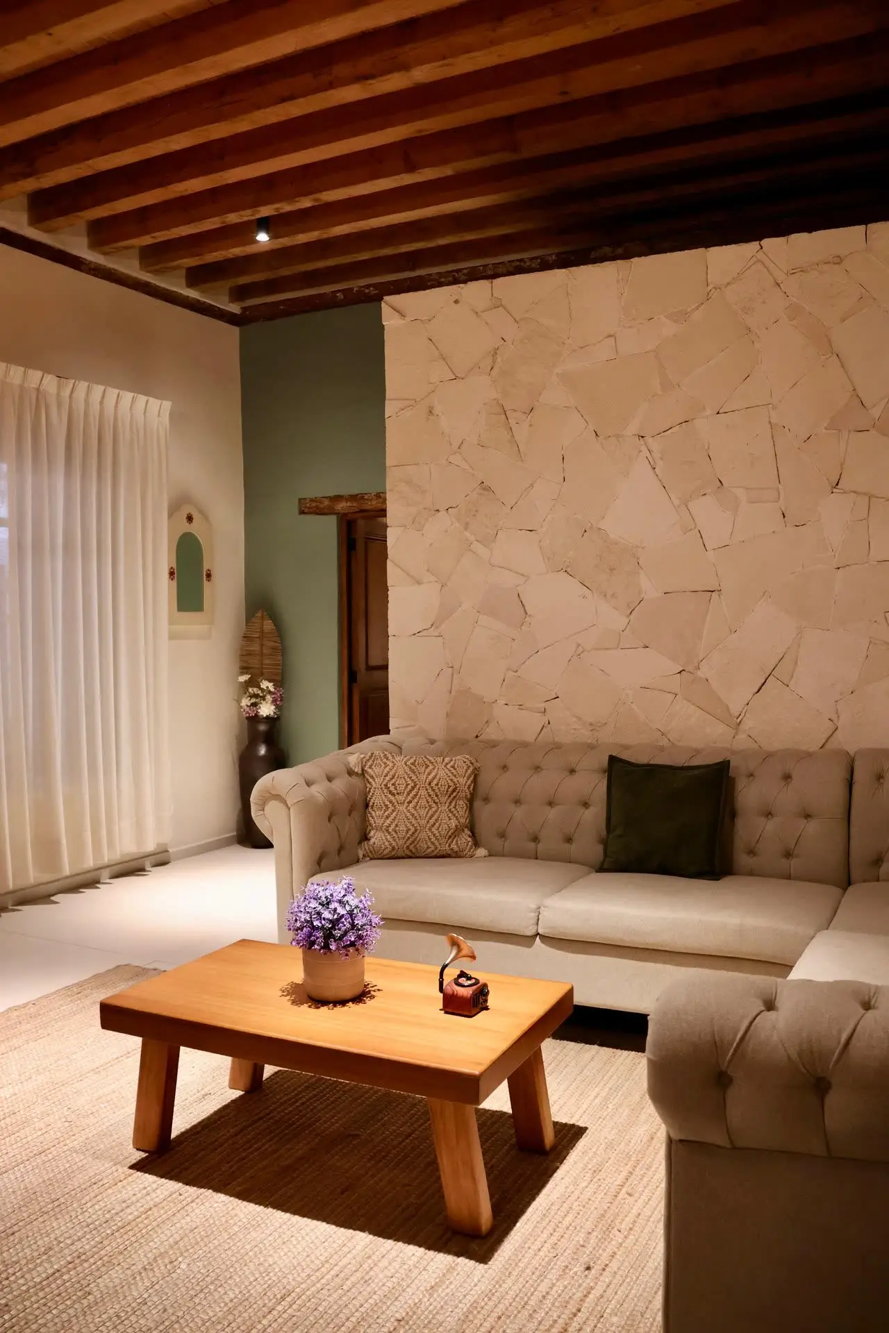 Sala del Departamento 1, con muro de piedra y vigas de madera