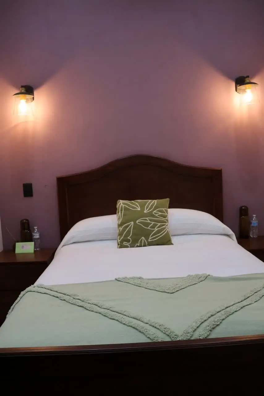 Recámara con cama matrimonial y pared malva