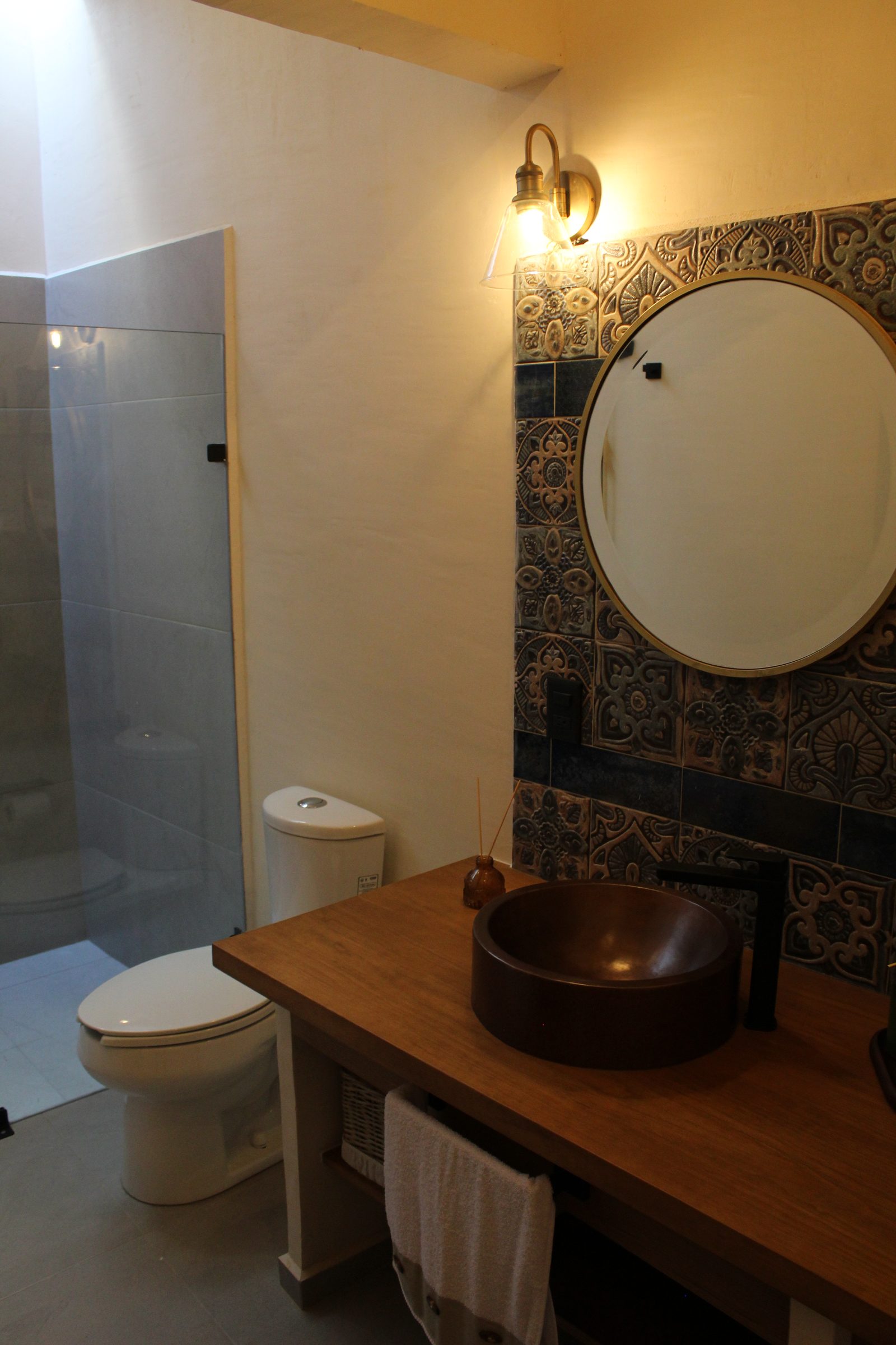 Baño con lavabo de cobre y espejo redondo