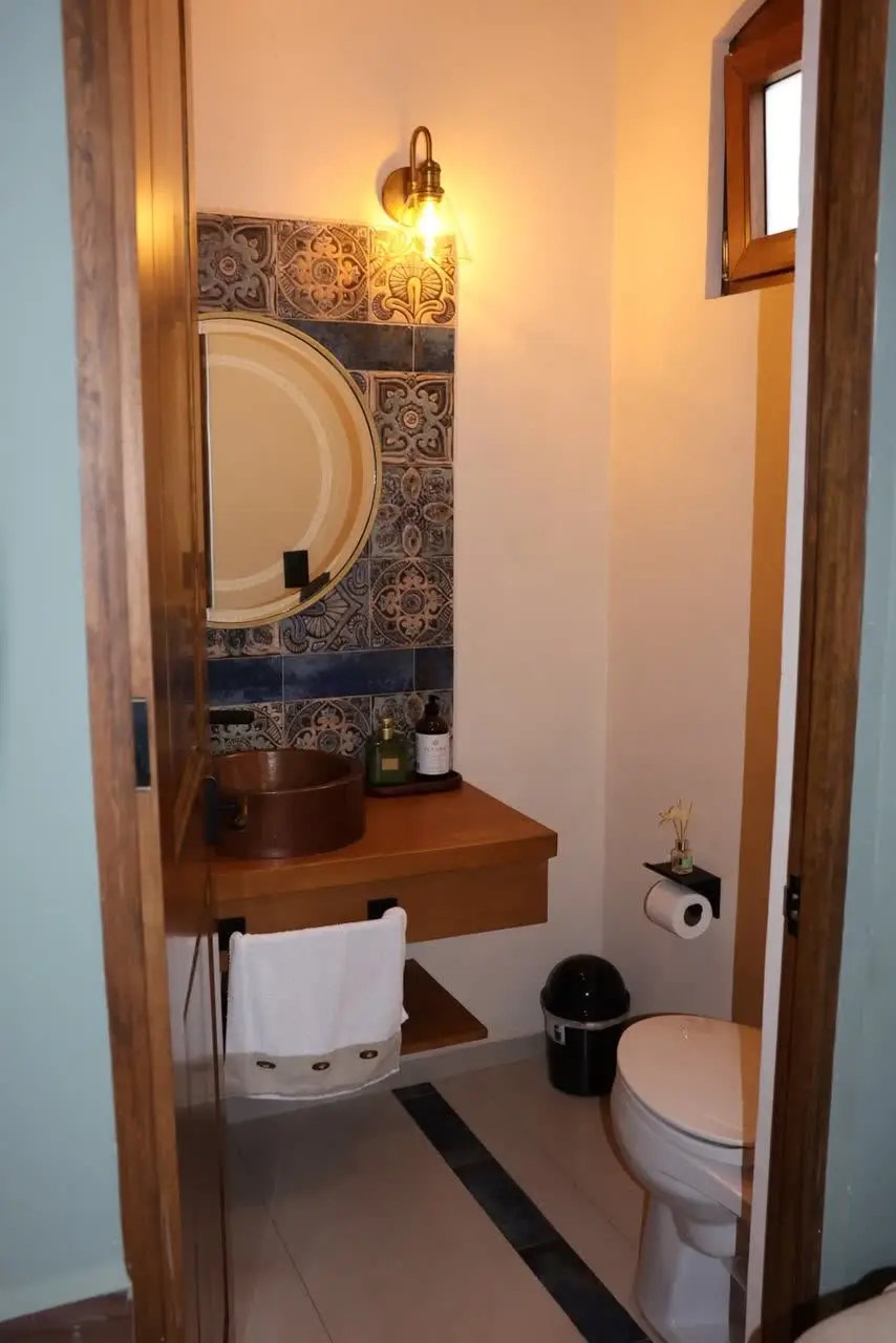 Baño con espejo redondo y mosaico talavera
