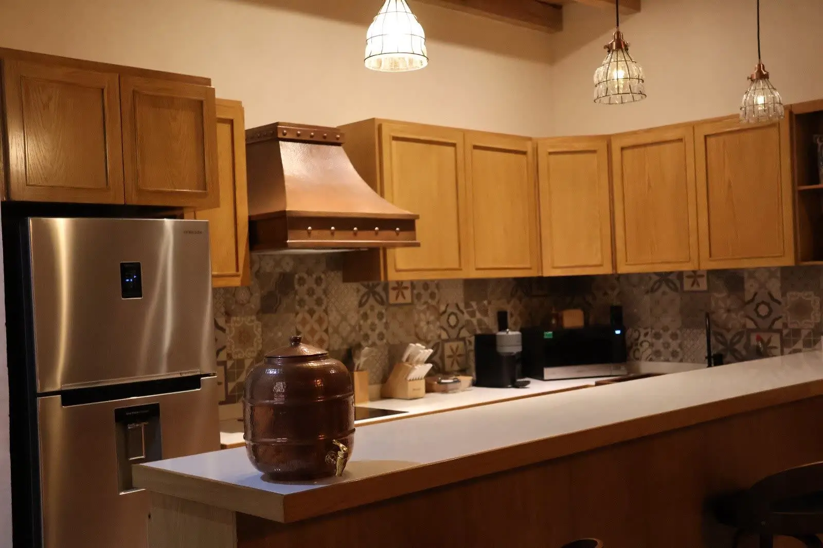 Cocina con campana de cobre, refrigerador y vigas de madera