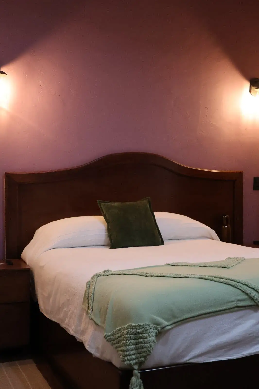 Recámara con cabecera de madera y cojín verde