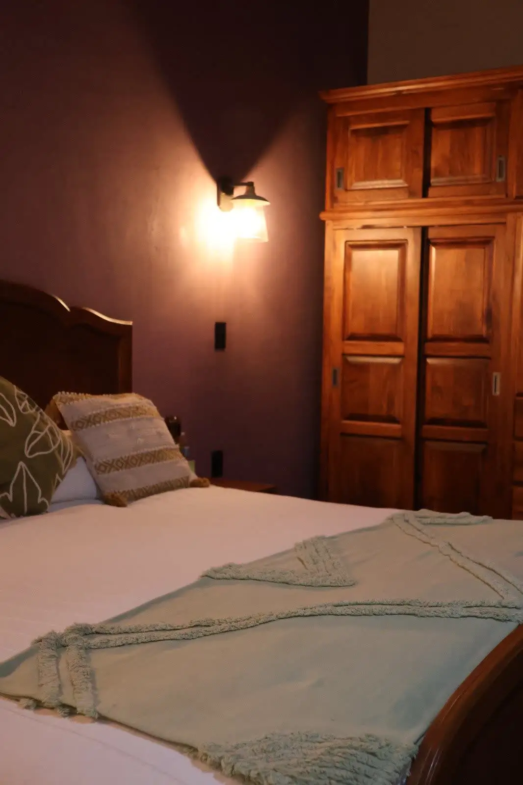 Detalle de manta verde a los pies de la cama